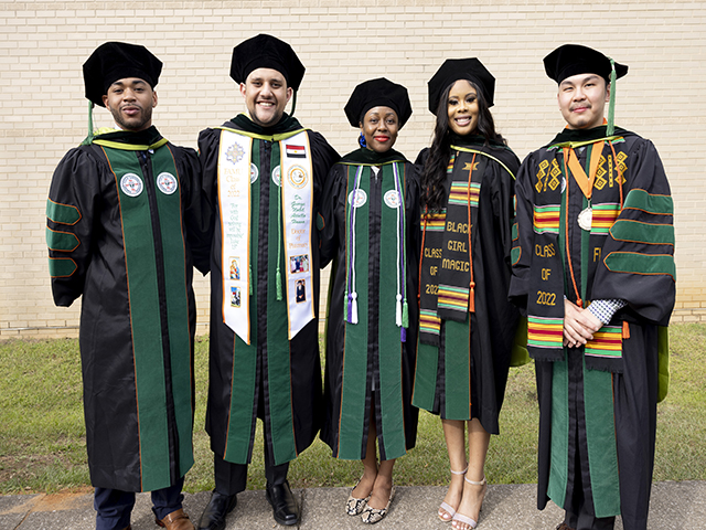 Five graduate students posing after graduation.