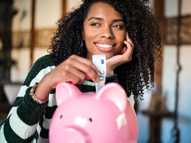 Girl putting money in a piggy bank